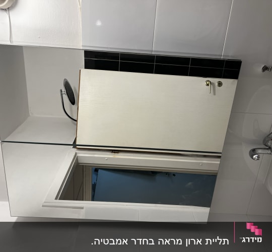 ארון מראה עם דלת פתוחה וחור בקיר
